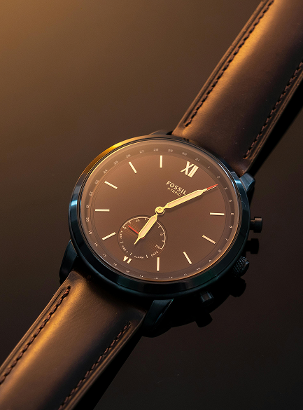 Watch with brown leather strap and dark face on a dark background