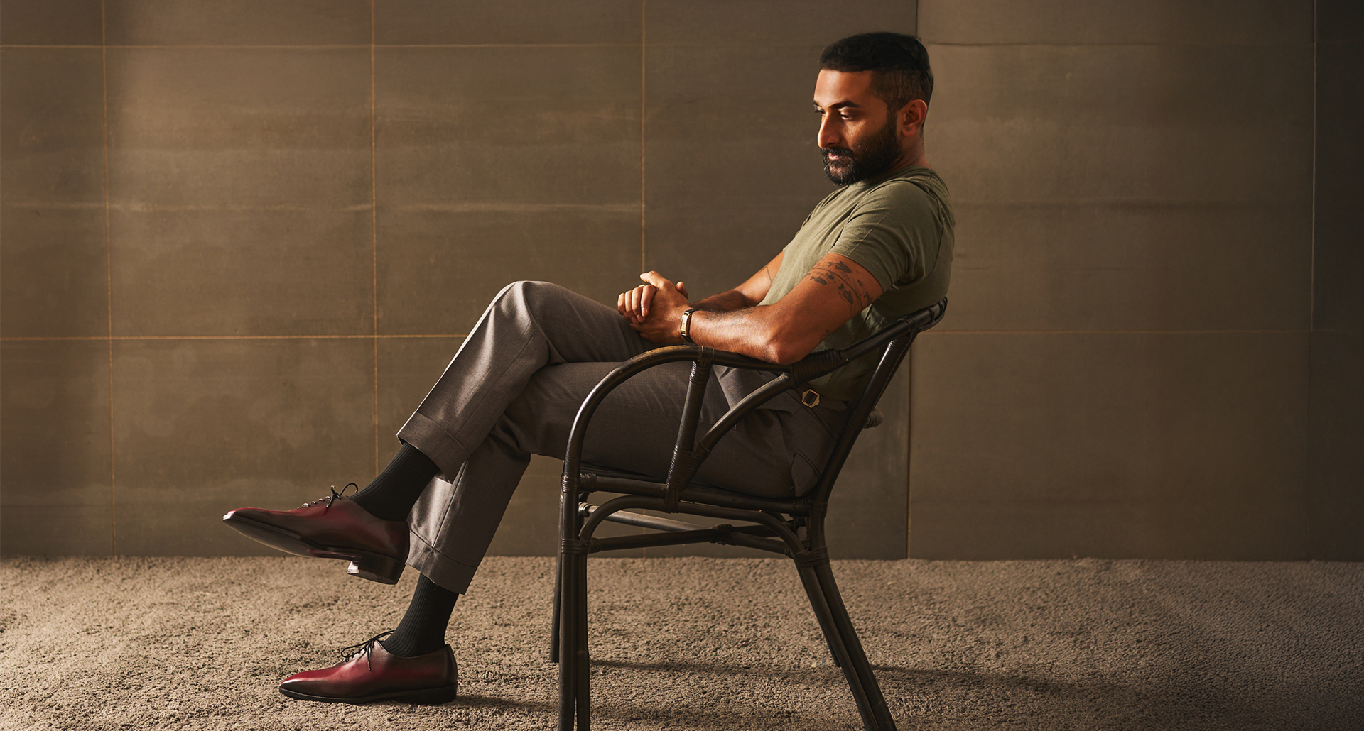 Man sitting on a chair against a textured wall.
