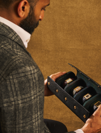 Man holding a jewelry box with rings against a brown background