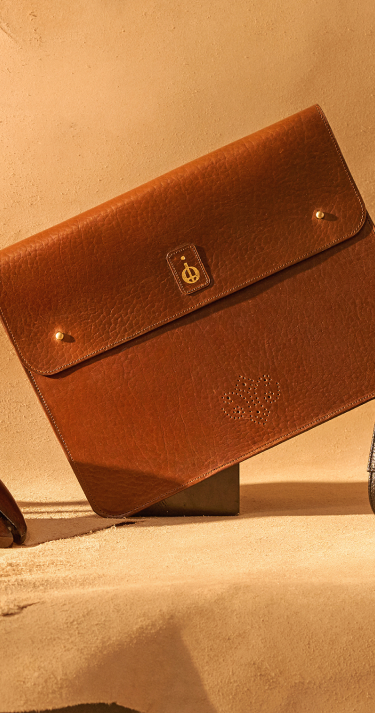 Brown leather clutch bag on a beige surface