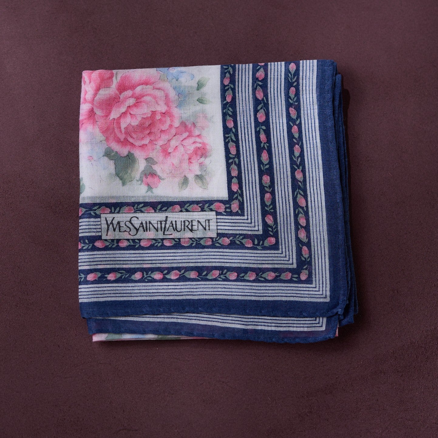 Folded Yves Saint Laurent handkerchief with floral design on a brown background