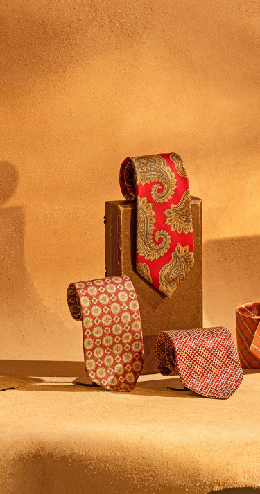 Three patterned ties on a textured beige surface