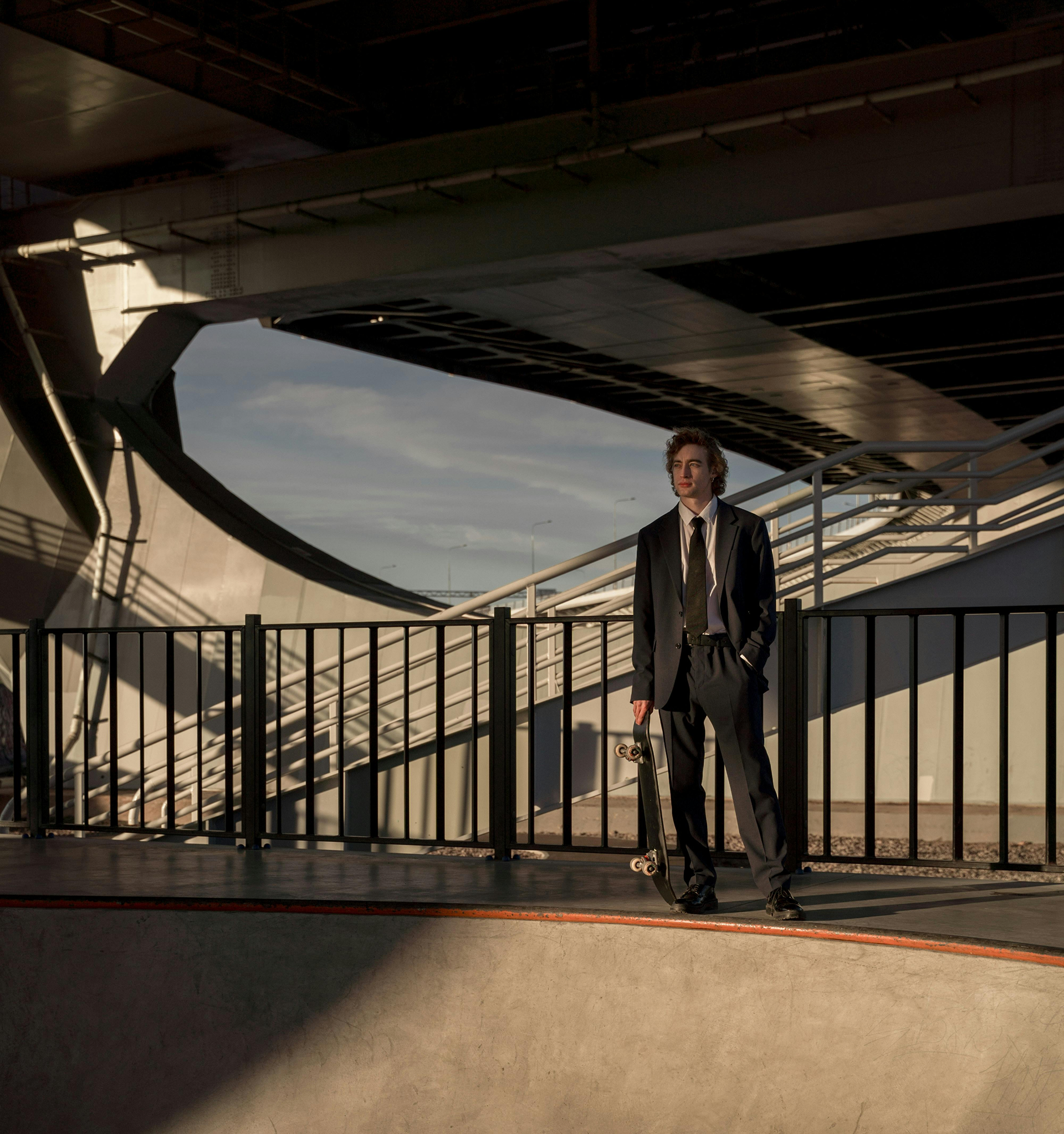 Man in a suit standing on a bridge with a scenic background